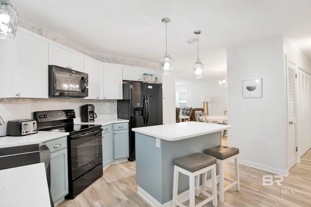 kitchen with decorative backsplash, light wood-style floors, a center island, black appliances, and a kitchen bar