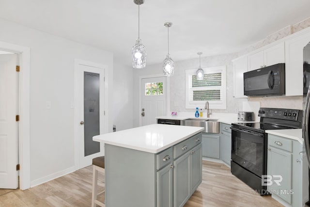 kitchen featuring a sink, gray cabinetry, a kitchen island, black appliances, and light wood finished floors