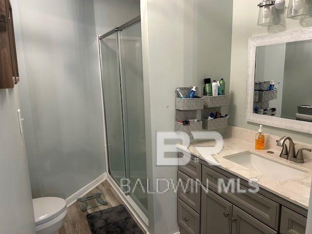 bathroom with wood finished floors, toilet, a shower stall, and vanity