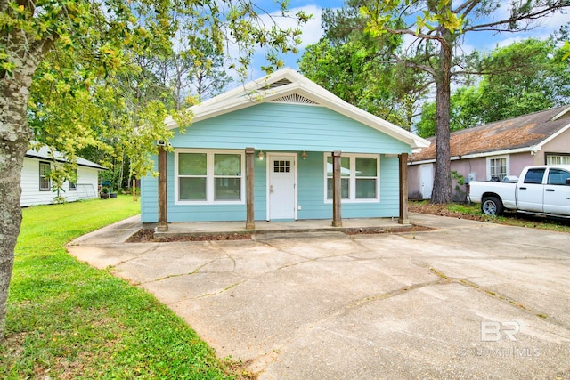 bungalow-style home featuring covered porch and a front yard