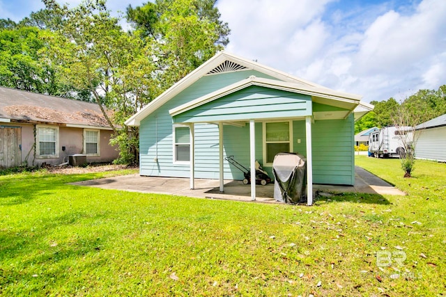 rear view of house with a patio, a yard, and central AC