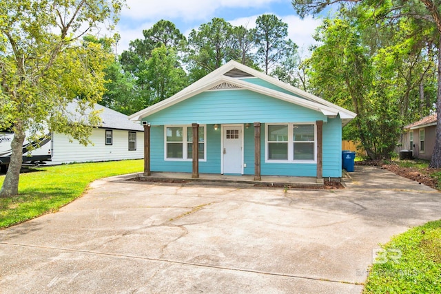 bungalow-style house featuring a front lawn, driveway, and covered porch