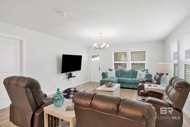 living room with a chandelier, baseboards, and light wood-style flooring