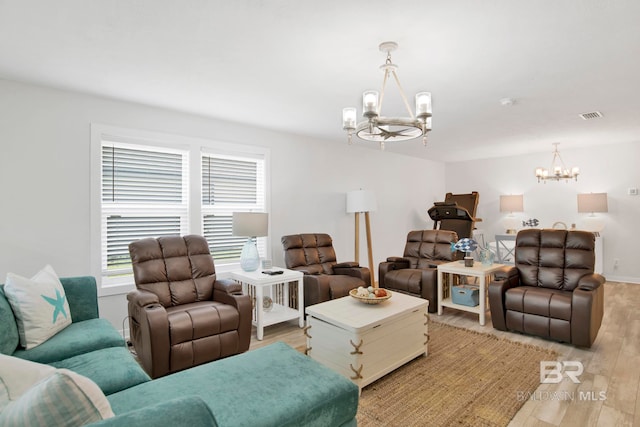 living area featuring visible vents, light wood-type flooring, and a notable chandelier
