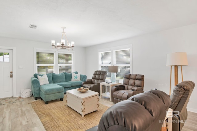 living area featuring light wood-type flooring, visible vents, a notable chandelier, and baseboards