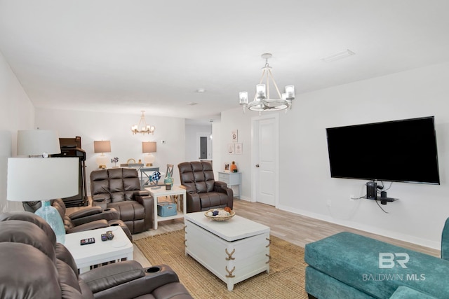 living room with light wood-style flooring, a chandelier, and baseboards