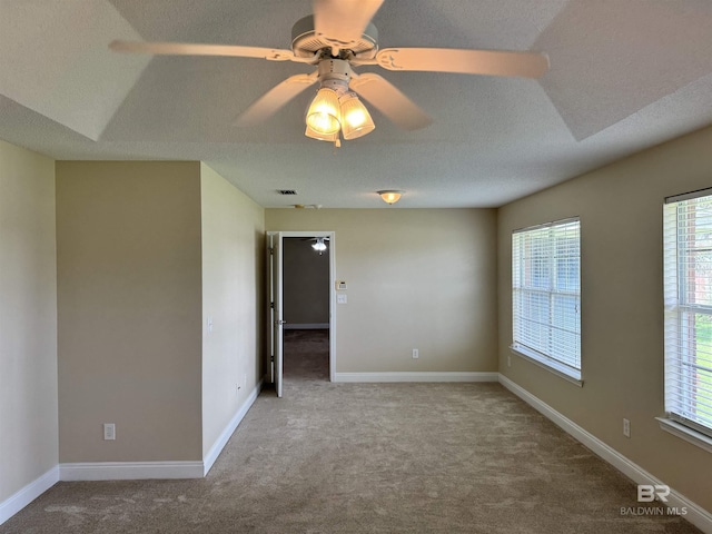 carpeted empty room with a textured ceiling, ceiling fan, visible vents, and baseboards