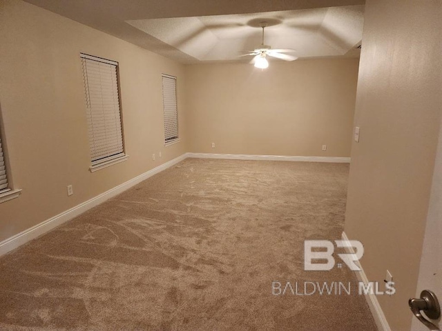 carpeted spare room featuring ceiling fan, baseboards, and vaulted ceiling