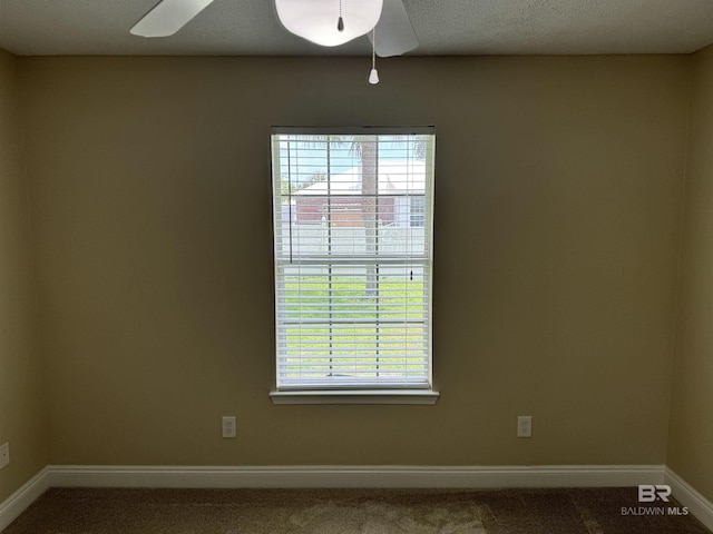 carpeted spare room featuring a textured ceiling, baseboards, and a ceiling fan