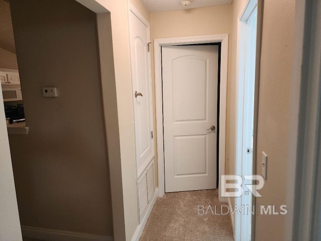 corridor featuring baseboards and light colored carpet