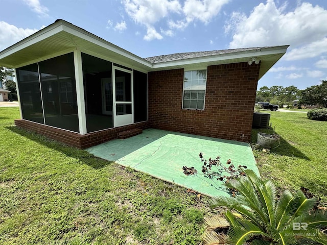 rear view of property featuring central AC unit, a sunroom, a yard, a patio area, and brick siding