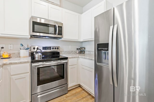 kitchen featuring light stone countertops, light hardwood / wood-style flooring, white cabinets, and stainless steel appliances