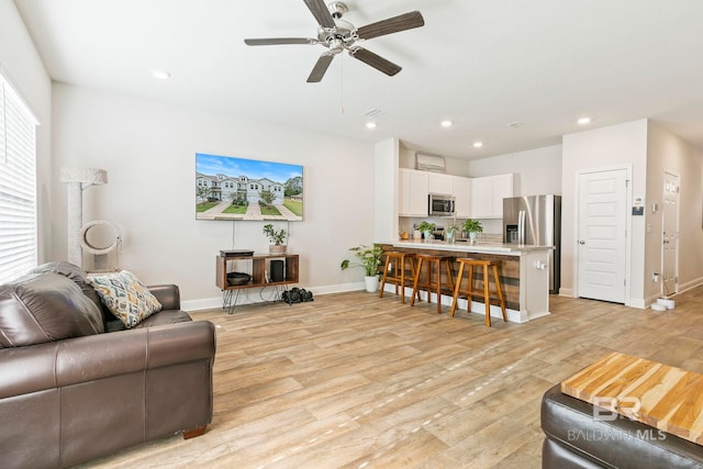 living room with ceiling fan and light hardwood / wood-style flooring