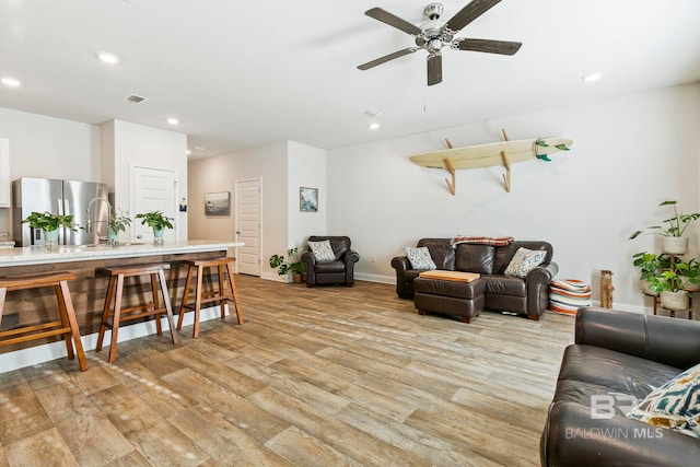 living room with ceiling fan and light hardwood / wood-style floors