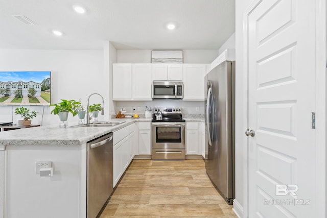 kitchen featuring white cabinetry, sink, stainless steel appliances, and light hardwood / wood-style flooring