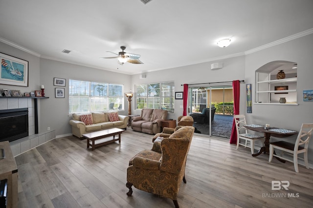 8585 Bay Harbor Rd, Elberta, AL 36530 - living area featuring crown molding, a ceiling fan, a tiled fireplace, and wood finished floors