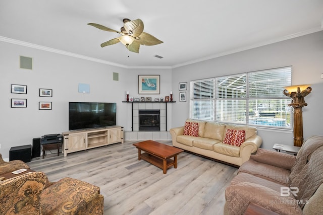 8585 Bay Harbor Rd, Elberta, AL 36530 - living area featuring light wood-type flooring, ornamental molding, a ceiling fan, and a tile fireplace