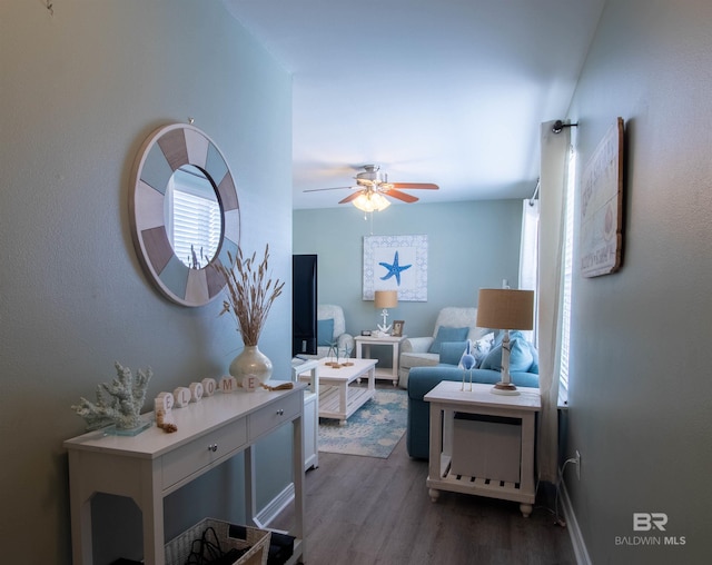 living area with a ceiling fan and dark wood-style flooring