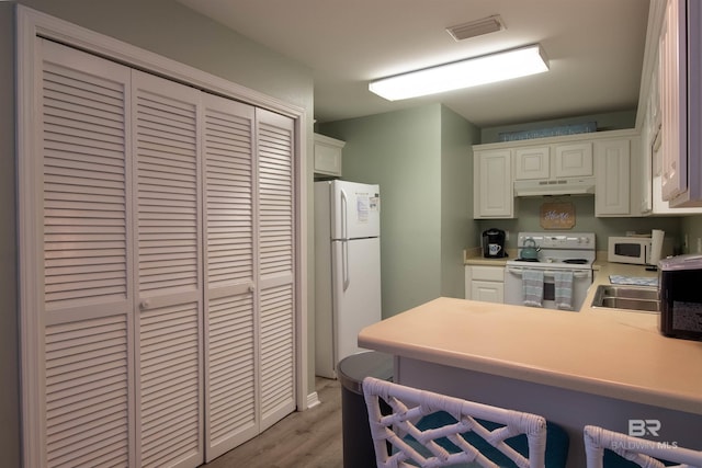 kitchen featuring under cabinet range hood, white appliances, visible vents, white cabinets, and light countertops