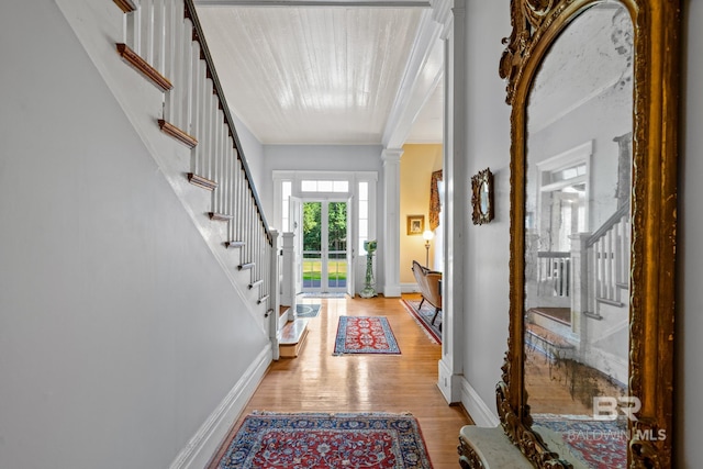 entrance foyer featuring light wood-type flooring, ornate columns, and crown molding