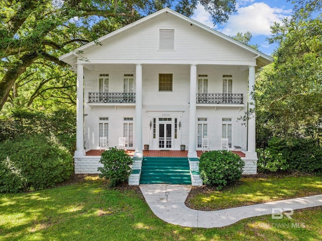 view of front facade with a porch, a balcony, and a front yard