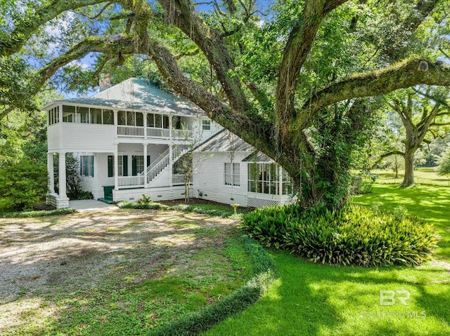 back of house with a sunroom and a lawn