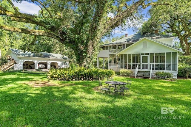 back of house featuring a lawn and a sunroom