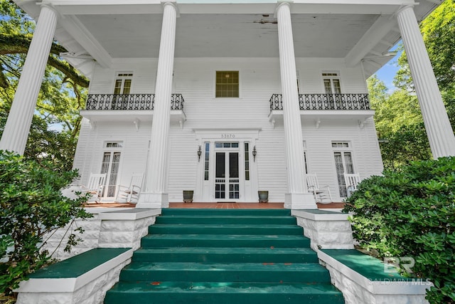 back of house with covered porch and a balcony