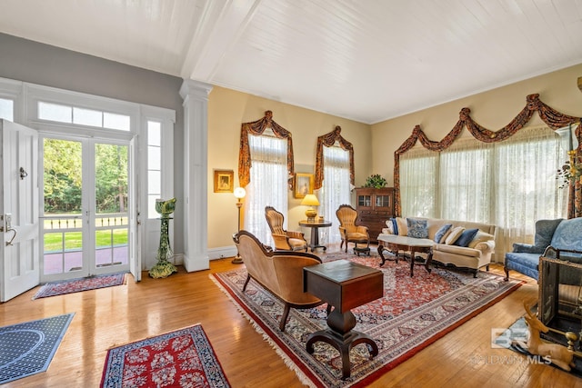 living room with french doors, light hardwood / wood-style flooring, ornate columns, beamed ceiling, and wood ceiling