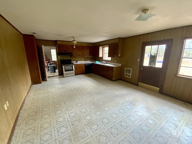 kitchen with sink, dishwasher, stainless steel range with electric stovetop, and wood walls