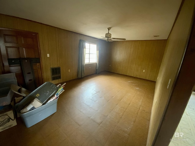 spare room featuring ceiling fan, wooden walls, and heating unit