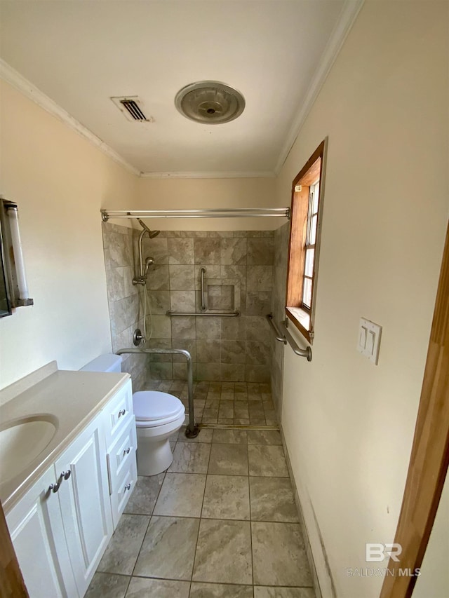 bathroom featuring crown molding, a tile shower, vanity, and toilet