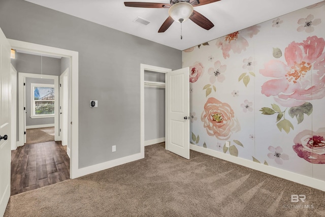 unfurnished bedroom with dark colored carpet, a closet, and ceiling fan