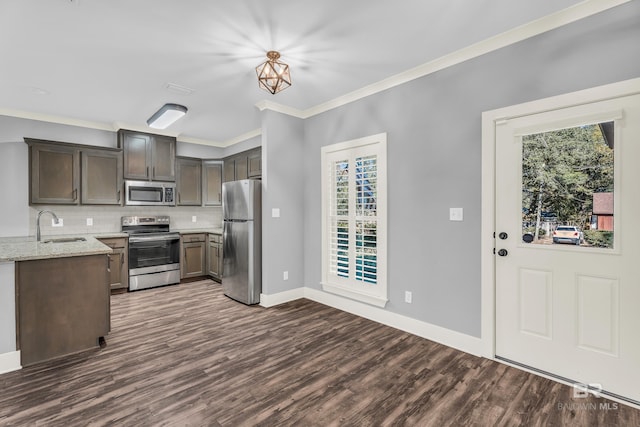 kitchen with appliances with stainless steel finishes, dark hardwood / wood-style flooring, tasteful backsplash, light stone counters, and sink