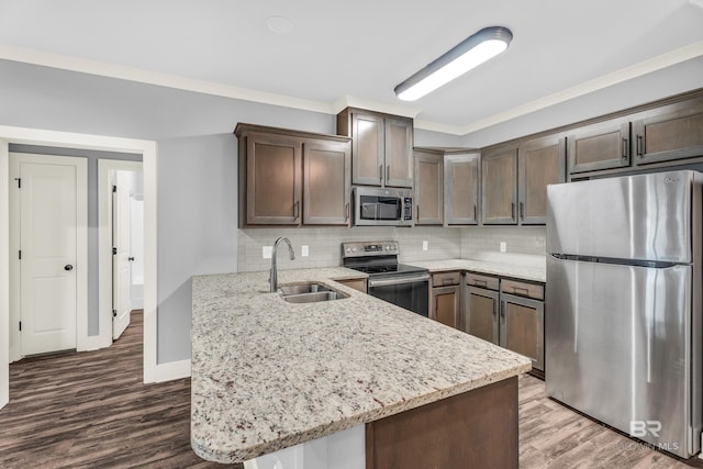 kitchen with appliances with stainless steel finishes, light stone counters, ornamental molding, dark brown cabinetry, and sink