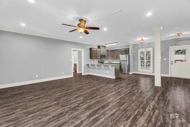 unfurnished living room with crown molding, ceiling fan, and dark wood-type flooring