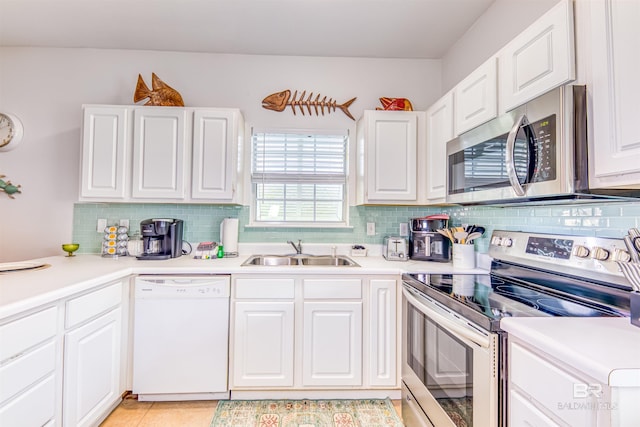 kitchen featuring appliances with stainless steel finishes, backsplash, white cabinetry, sink, and light tile floors