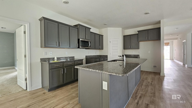 1897 Carly St, Foley, AL 36535 - kitchen featuring stainless steel microwave, a sink, dark stone countertops, light wood-style floors, and baseboards