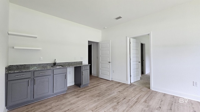 1897 Carly St, Foley, AL 36535 - kitchen with open shelves, a sink, light wood finished floors, dark stone counters, and gray cabinetry