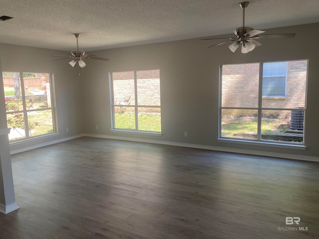 unfurnished room featuring ceiling fan, a healthy amount of sunlight, dark hardwood / wood-style floors, and a textured ceiling