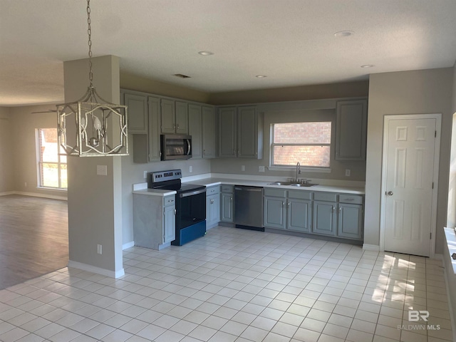 kitchen with sink, appliances with stainless steel finishes, light tile flooring, and hanging light fixtures