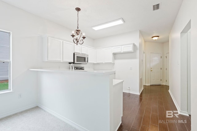 kitchen featuring white cabinetry, kitchen peninsula, hanging light fixtures, and dark hardwood / wood-style floors