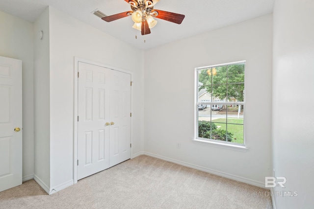 unfurnished bedroom featuring ceiling fan, a closet, and light colored carpet