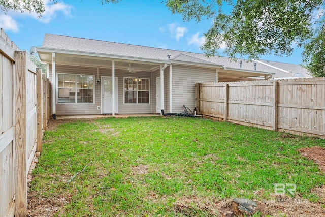 rear view of house featuring ceiling fan and a yard