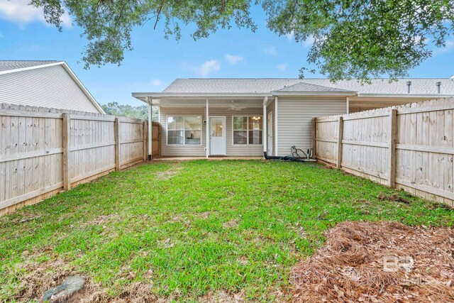 rear view of property with a yard and ceiling fan