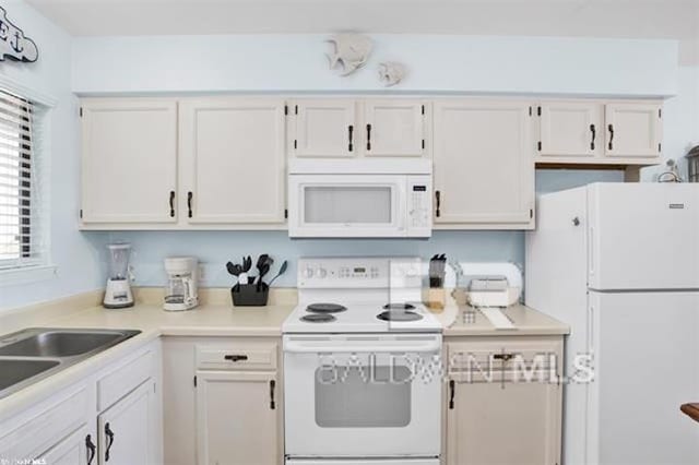 kitchen featuring light countertops, white appliances, and white cabinetry