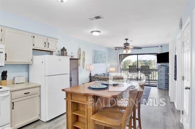 kitchen featuring range with electric cooktop, visible vents, light wood-style flooring, freestanding refrigerator, and white cabinetry