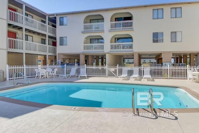 community pool featuring fence and a patio