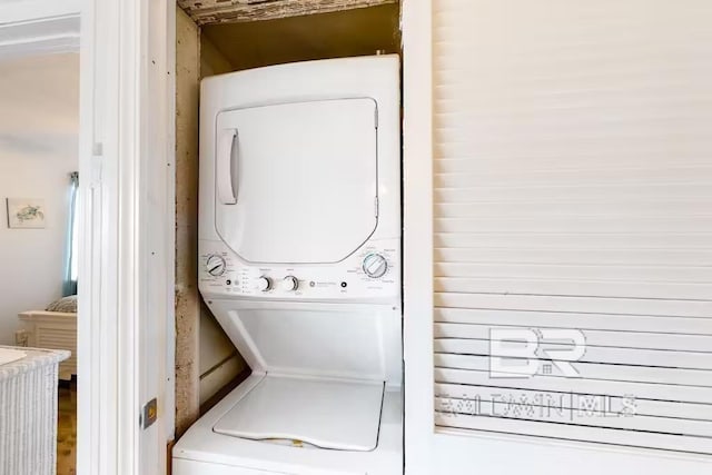 clothes washing area with stacked washer and dryer and laundry area