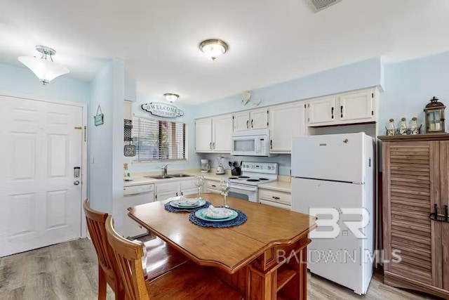 kitchen featuring light countertops, white appliances, white cabinetry, and a sink